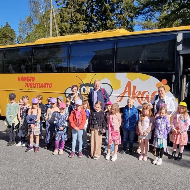 Nahkialan koulun oppilaat ja henkilökuntaa seisoo keltaisen bussin edessä.