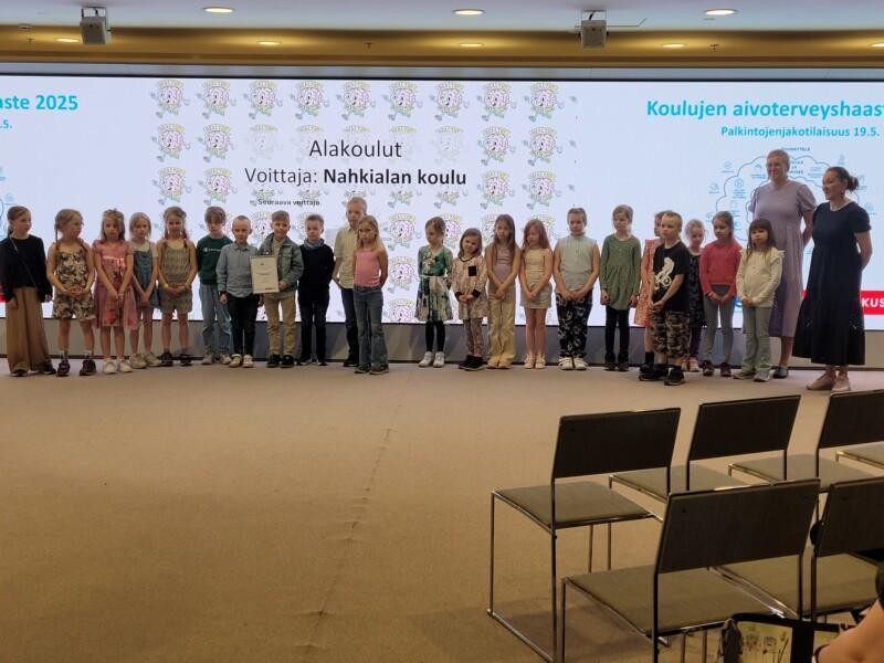 Nahkialan koulun oppilaat seisovat rivissä palkintojenjakotilaisuudessa Helsingin kaupungintalolla.