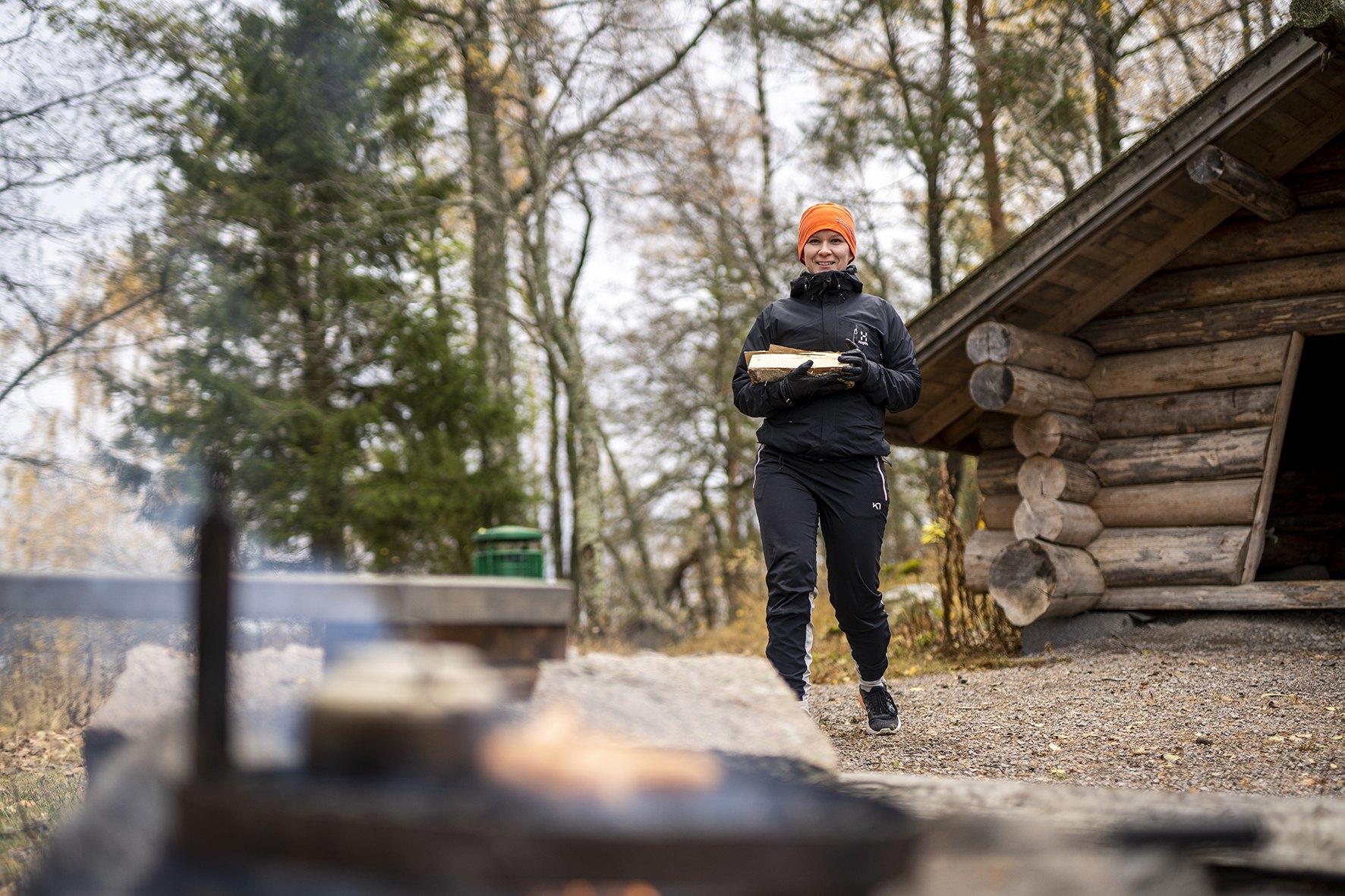 Laavu jossa nainen kantaa puita.